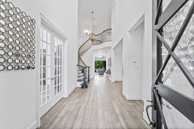 This home has a beautiful 2 story entrance with wood flooring, custom lighting and wrought iron staircase.