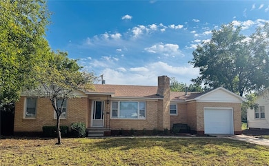 Ranch-style house featuring brick siding, a garage, and a front lawn