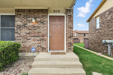 View of exterior entry with brick siding and a lawn