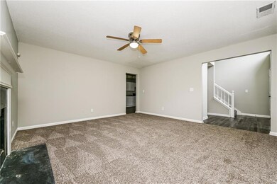Unfurnished living room with carpet floors, a ceiling fan, stairs, and a fireplace