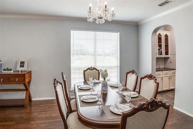 Dining area featuring crown molding, dark wood-style flooring, and a chandelier