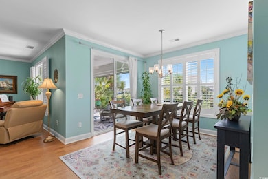 Dining area with ornamental molding, light wood-style flooring, and a chandelier