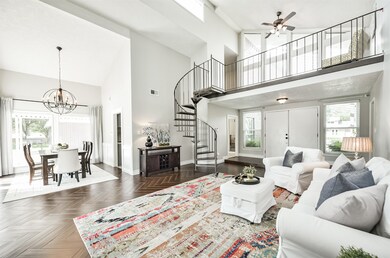 An alternate view of the family room highlights the numerous windows that cast abundant natural light into this space. The circular staircase leads up to a loft sitting area and an additional enclosed space that is perfectly suited for a home office or play space.