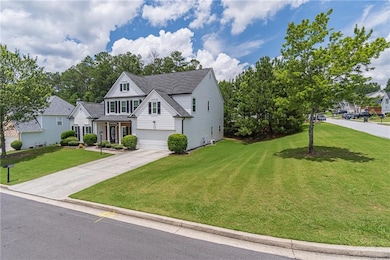 Traditional-style house featuring an attached garage, concrete driveway, a front yard, and roof with shingles