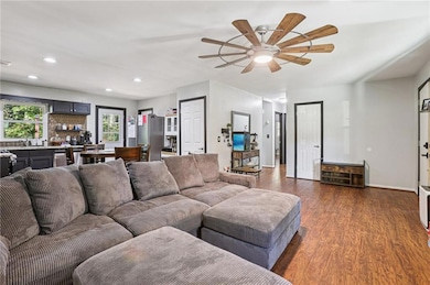 Living room with dark wood-style floors, recessed lighting, and ceiling fan
