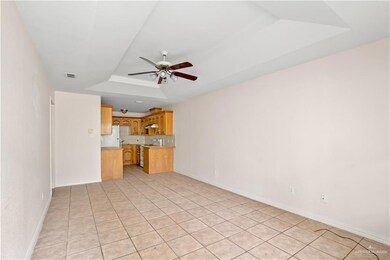 Unfurnished living room featuring a tray ceiling, light tile patterned floors, and ceiling fan