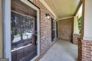 Entrance to property with covered porch and brick siding