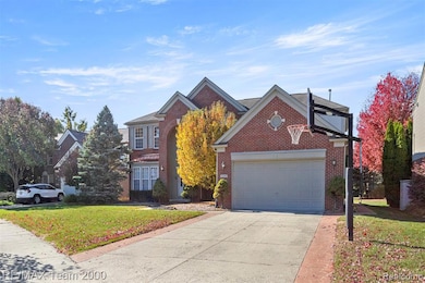 Traditional home featuring a front yard, concrete driveway, brick siding, and a garage