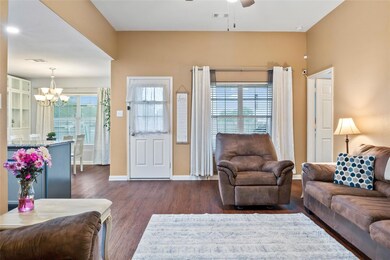 Living room featuring ceiling fan with notable chandelier and dark hardwood / wood-style floors