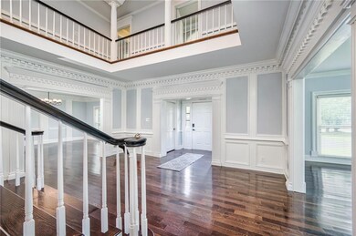 Foyer featuring crown molding, dark wood finished floors, a chandelier, a towering ceiling, and a decorative wall