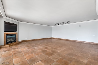 Spare room with ornamental molding, a fireplace, track lighting, and baseboards