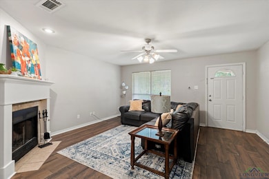 Living room with a ceiling fan, wood finished floors, and a tiled fireplace