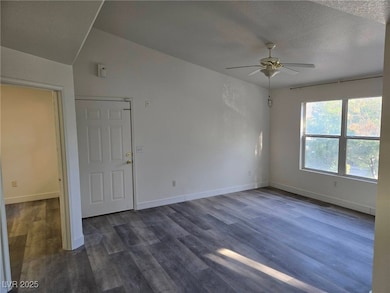 Empty room with ceiling fan and dark wood-style fl