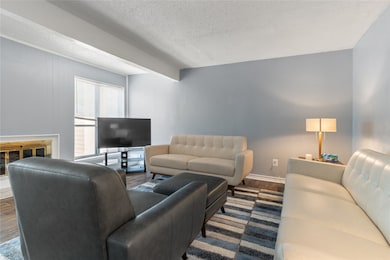 Living area featuring wood finished floors, a textured ceiling, and beam ceiling