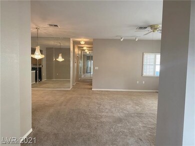 Carpeted empty room featuring baseboards, visible vents, rail lighting, and ceiling fan