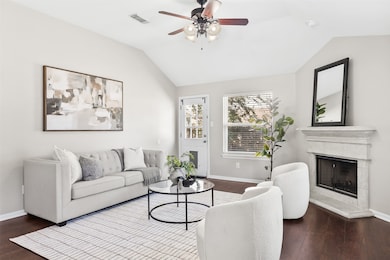 The living room feels bright and serene, anchored by a gas-log fireplace and bathed in natural light—creating a warm space for everyday living or relaxed entertaining.