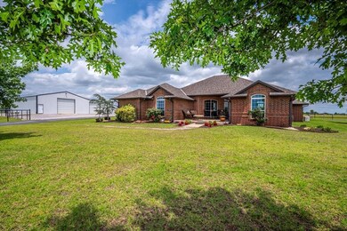 View of front of home with barn/shop, brick siding, asphalt driveway, and roof with shingles