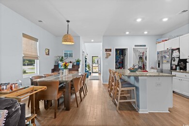 Kitchen with stainless steel fridge, light wood finished floors, light stone countertops, healthy amount of natural light, and recessed lighting