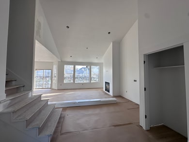 Unfurnished living room featuring a glass covered fireplace and stairs