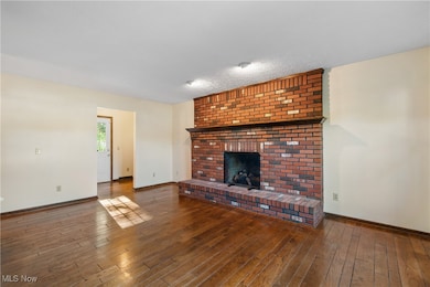 Unfurnished family room with a brick fireplace and dark wood floors