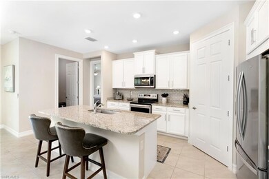Kitchen with sink, white cabinets, light stone cou