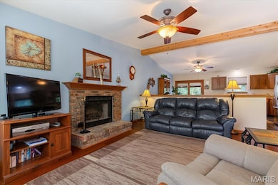 Living area with wood finished floors, a fireplace, and a ceiling fan