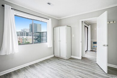 Unfurnished bedroom with light wood-style floors, a view of city, and crown molding