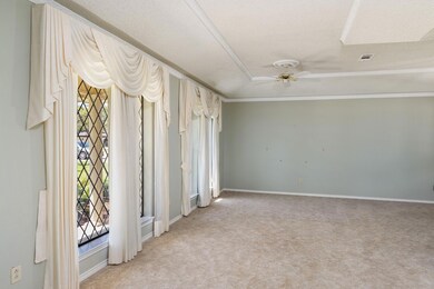 The living room has a view of big trees and mature
