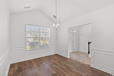 Unfurnished room featuring a chandelier, dark wood