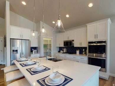 Kitchen with light wood-style floors, decorative backsplash, appliances with stainless steel finishes, white cabinets, and recessed lighting