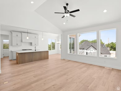 Kitchen with light countertops, open floor plan, a kitchen island with sink, plenty of natural light, and high vaulted ceiling