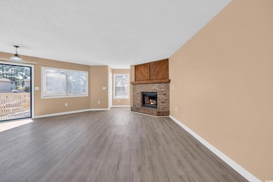Unfurnished living room with wood finished floors, a fireplace, and a textured ceiling