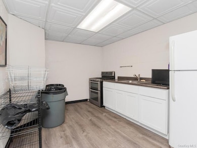 Kitchen with double oven range, freestanding refrigerator, dark countertops, a sink, and white cabinets