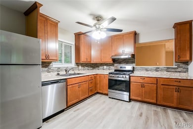 Kitchen featuring stainless steel appliances, backsplash, and brown cabinets