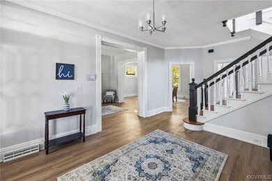 Entrance foyer featuring a notable chandelier, dark wood-type flooring, and crown molding