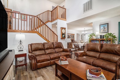 Living area with a chandelier, a towering ceiling, light wood-style floors, and stairs