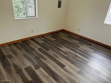 Empty room with dark wood-style flooring and baseboards