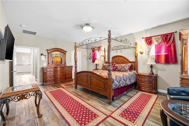 Primary bedroom with wood finished floors and baseboards