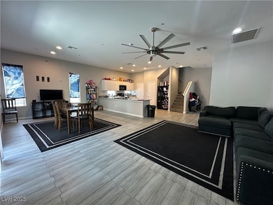 Living area with ceiling fan, stairway, recessed l