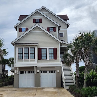 Raised beach house with concrete driveway, stairs, a garage, a shingled roof, and board and batten siding