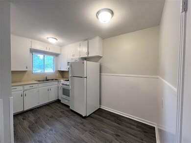 Kitchen with white appliances, dark wood-style fl