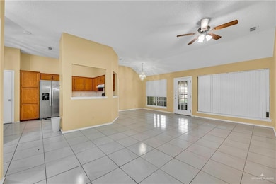 Unfurnished living room with light tile patterned floors, a textured ceiling, a chandelier, a ceiling fan, and lofted ceiling
