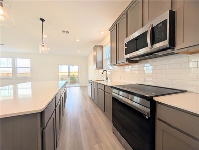 Kitchen featuring appliances with stainless steel finishes, hanging light fixtures, tasteful backsplash, light wood-type flooring, and recessed lighting