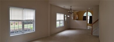 Carpeted spare room featuring a chandelier and baseboards