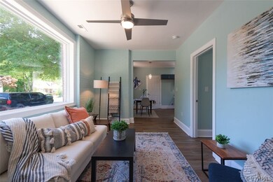 Living room with ceiling fan and dark wood-type fl