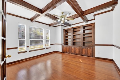 Spare room with coffered ceiling, beamed ceiling, light wood finished floors, a ceiling fan, and crown molding