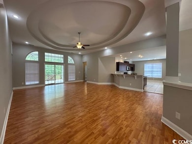 Unfurnished living room with a raised ceiling, recessed lighting, ceiling fan, and light wood finished floors