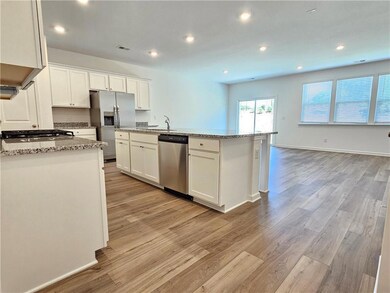 Kitchen featuring stainless steel appliances, white cabinets, light stone countertops, and recessed lighting