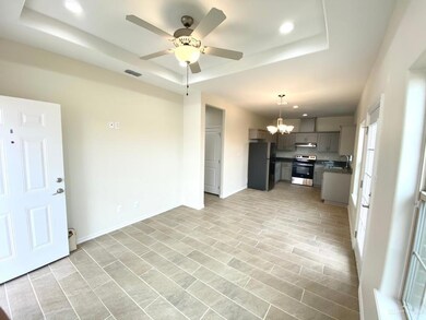 Unfurnished living room featuring a raised ceiling, a chandelier, recessed lighting, and a ceiling fan
