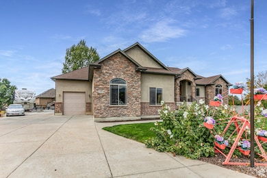 View of front of property featuring stucco siding, driveway, an attached garage, and stone siding